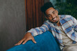 © ViDi Studio - Close up young smiling happy man wear casual shirt sits on blue sofa couch look camera stay at home hotel flat rest relax spend free spare time in living room indoors grey wall. People lounge concept.