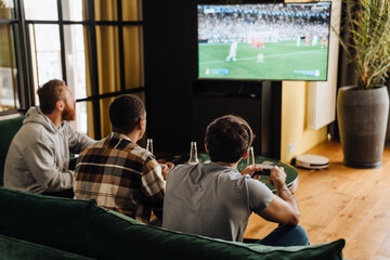 Poster - Back view of men playing football video game with gamepads at home