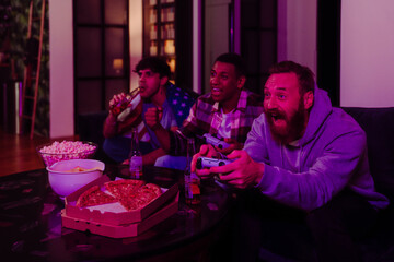 Canvas Print - Excited male friends playing video games and eating popcorn in dark living room