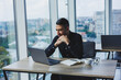 © Дмитрий Ткачук - A smiling businessman in a black shirt is sitting at a desk using a laptop. A person works in the office on a computer, analyzes data. Internet marketing, adult education, e-learning.