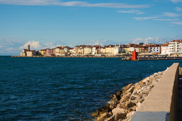 Wall Mural - The waterfront of the historic medieval town of Piran on the coast of Slovenia. Background left is the Our Lady of Health Church and a 17th century lighthouse tower
