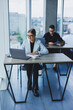 © Дмитрий Ткачук - A female manager is sitting at a desk using a laptop in a modern office against the background of a colleague. Working atmosphere in the office.