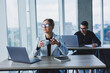 © Дмитрий Ткачук - Working atmosphere in an office with large windows. A female manager is sitting at a desk using a laptop in a modern office against the background of a colleague.