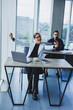 © Дмитрий Ткачук - Working atmosphere in an office with large windows. A female manager is sitting at a desk using a laptop in a modern office against the background of a colleague.