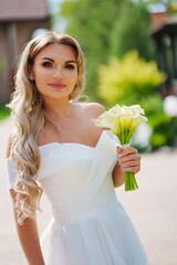 Wall Mural - a blonde bride with bouquet Calla Lily in a white dress. wedding fashion