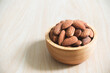 Almonds in brown wooden bowl on wooden table background