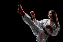 Girl Exercising Karate Leg Kick Wearing Kimono And Red Gloves Against Black Background