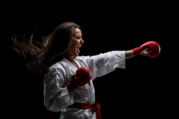 girl exercising karate punch and screaming against black background