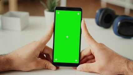 Poster - male freelancer looking at greenscreen display on smartphone app, using telephone with isolated back