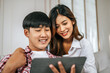 © Johnstocker - Young Asian couple enjoy with tablet together in living room