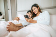 © Johnstocker - Young Asian couple enjoy with mobile phone in bedroom