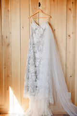 Wall Mural - Simple wedding dress hung up against wood wall with the veil tucked in. 