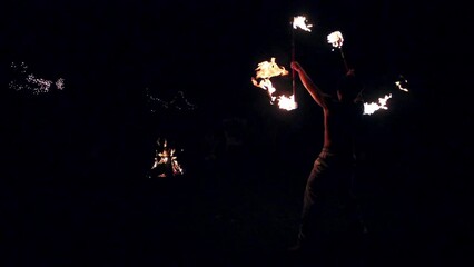 Wall Mural - Slow motion of a performer doing tricks with burning fire torches in the dark