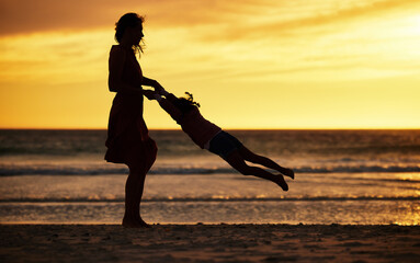 Wall Mural - Family, silhouette and sunset at beach with mother swinging child against yellow sky with love, care and support on vacation in summer. Woman and kid by sea for travel fun, adventure and freedom