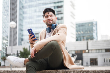 young american man using smartphone sitting outdoors