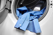 Close-up of an open door in washing machine with dirty shirts inside