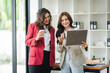 © Daenin - Two female designers smile at the camera as they work together at a conference room table during a meeting in a modern office. collaboration concept