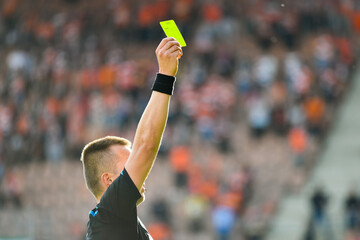 Wall Mural - Referee shows yellow card during soccer match at the stadium.