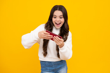 Canvas Print - Excited teenager girl use smart phone, share social media, chatting by mobile phone wear stylish casual trendy clothes isolated over yellow background. Child with smartphone.