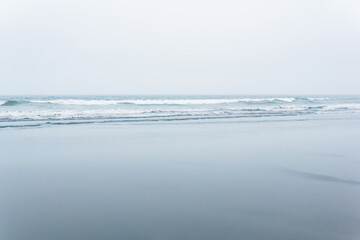 foggy seascape, cold ocean shore with a wide beach