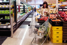 Woman Looking At Shopping List In Supermarket