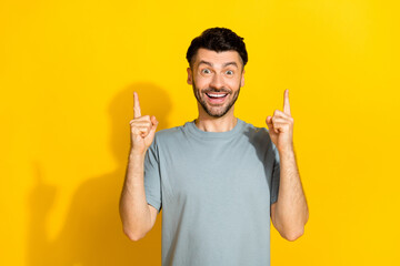 Wall Mural - Photo of funky excited positive brunet man student genius idea solution cash problem eureka success fingers pointing up isolated on yellow color background