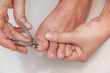 Woman cutting nails using nail clipper on white background