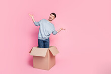 Full Size Photo Of Handsome Young Guy Stand Carton Box Raise Hands Empty Space Dressed Trendy Blue Look Isolated On Pink Color Background