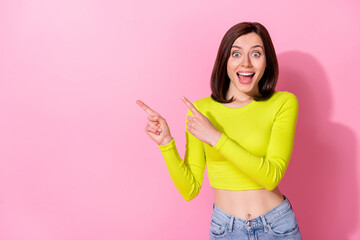 Poster - Photo of excited funky lady wear yellow top looking pointing two fingers empty space open mouth isolated pink color background