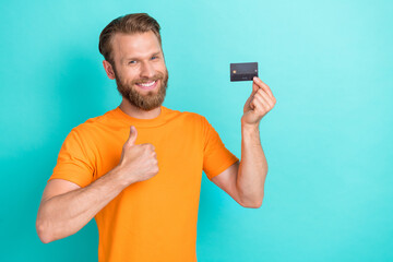 Wall Mural - Photo of boss beard guy hold card thumb up wear orange t-shirt isolated on teal color backgroiund