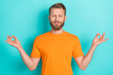 Wall Mural - Photo of concentrated meditating good mood man with blond hairstyle dressed orange t-shirt eyes closed isolated on teal color background
