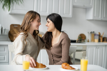 Sticker - Side view of positive lesbian couple looking at each other near breakfast in kitchen