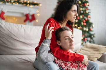 Sticker - Same sex couple in christmas sweaters hugging on couch at home