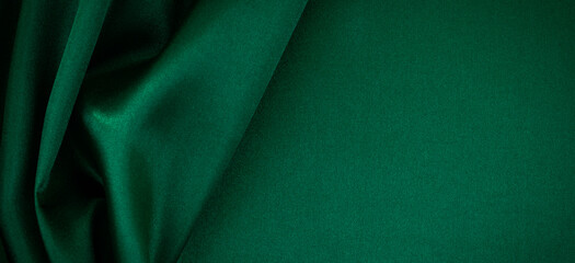 Abstract monochrome elegant luxury cloth background. Green color background with drapery and wavy folds of luxurious silk satin material. Top view