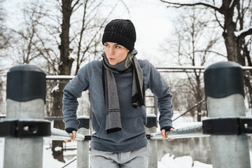 Wall Mural - Athletic woman during her winter outdoor workout on parallel bars