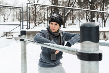 Wall Mural - Athletic woman during her winter outdoor workout on parallel bars