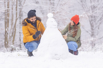 Wall Mural - Couple making snowman while on winter vacation