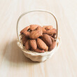 Almonds in a brown woven basket on wooden table background