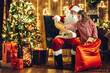 © ZaStock - Santa Clause and her little helper girl checking to see if all gifts on the wishlist are in sack.