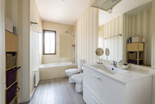 Spacious Bathroom With Square Frameless Mirror, Glass Enclosed Shower Stall, Sink Cabinet And White Toilet Bowls