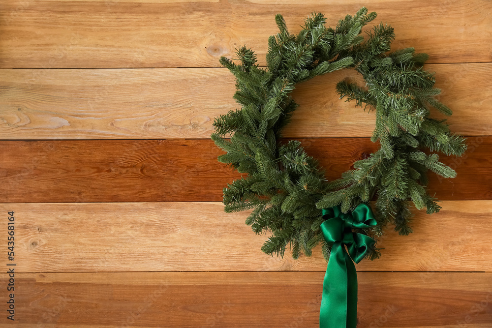 Stylish Christmas wreath hanging on wooden wall