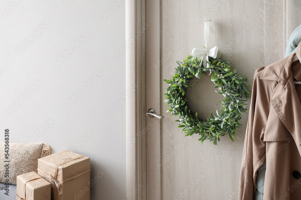 Christmas mistletoe wreath hanging on door in room