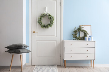 Stylish Christmas mistletoe wreath hanging on door in room