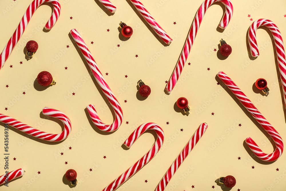 Composition with sweet candy canes and Christmas balls on color background