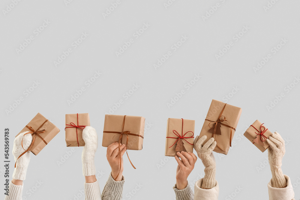 People with Christmas gift boxes on grey background