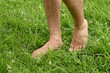 Male bare feet walking on the grass, walking on the sunlight. Practicing yoga, walking barefoot,man walking barefoot on green grass.Closeup