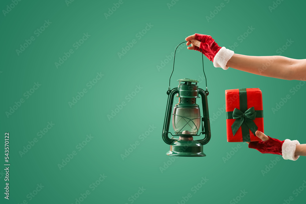 Woman with Christmas gift box and lantern on green background