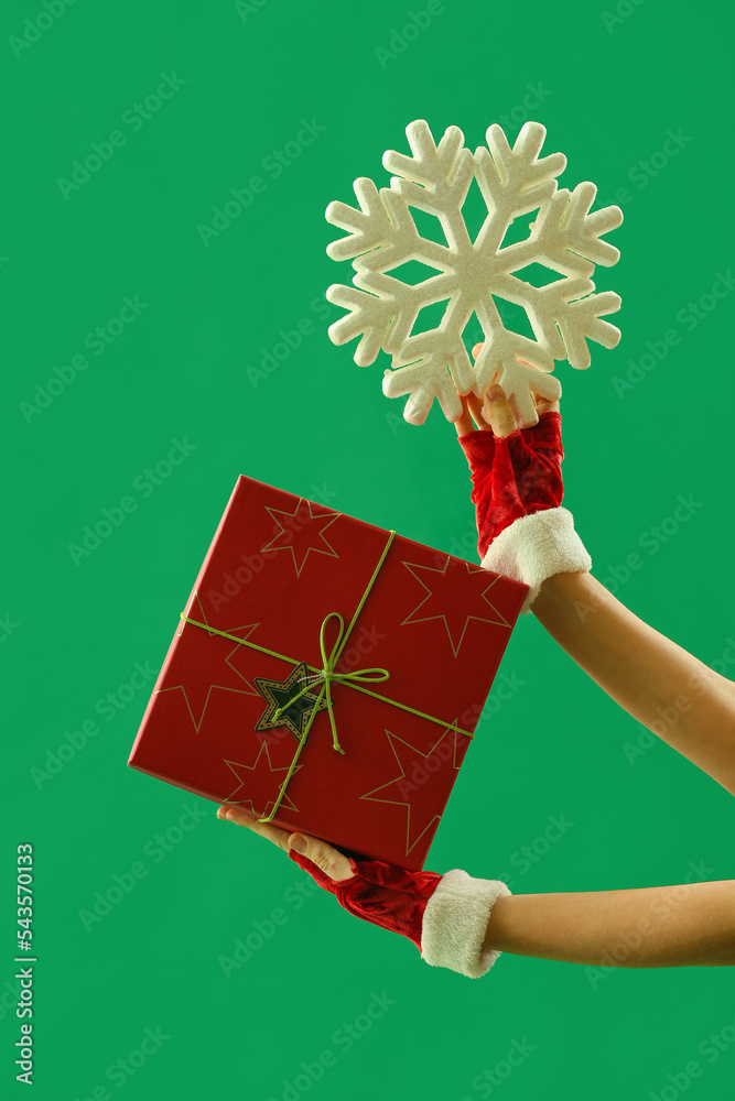 Woman with Christmas gift box and snowflake on green background