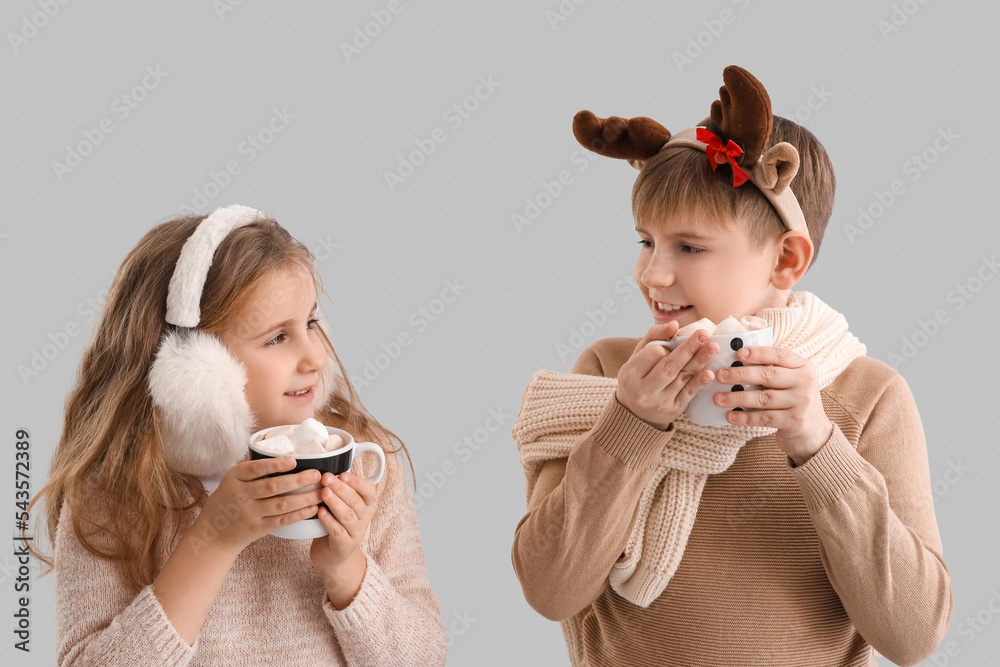 Little children with cups of cocoa on grey background