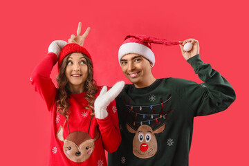 Canvas Print - Loving couple in Christmas sweaters on red background